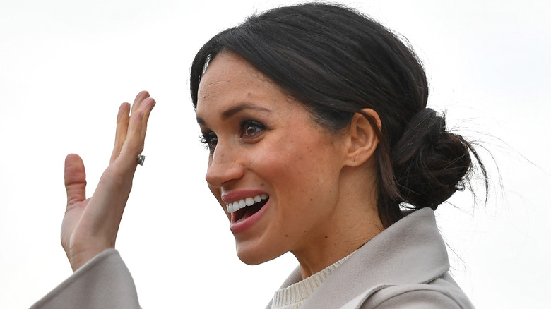 Meghan Markle with messy bun waving 