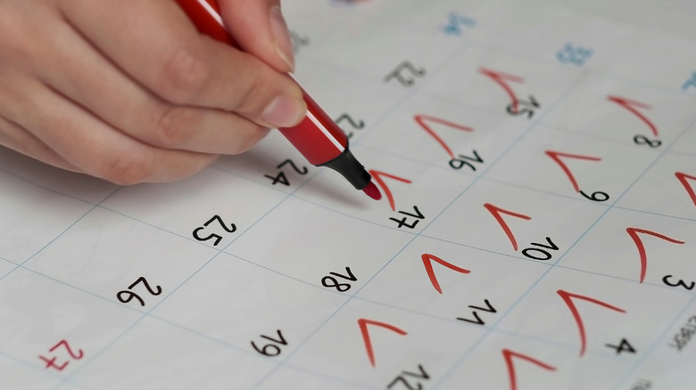 Person marking a calendar with red marker