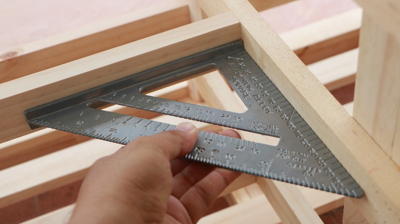 A person measuring a wooden right angle