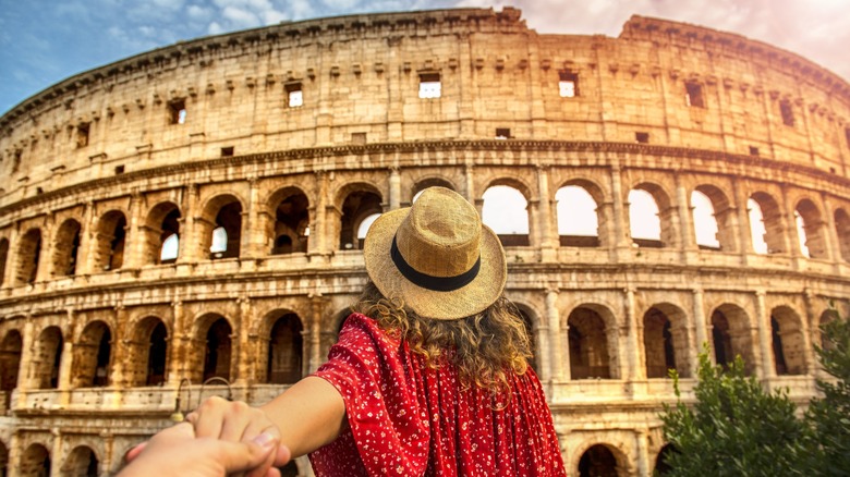 A woman holding someone's hand while looking at The Colosseum