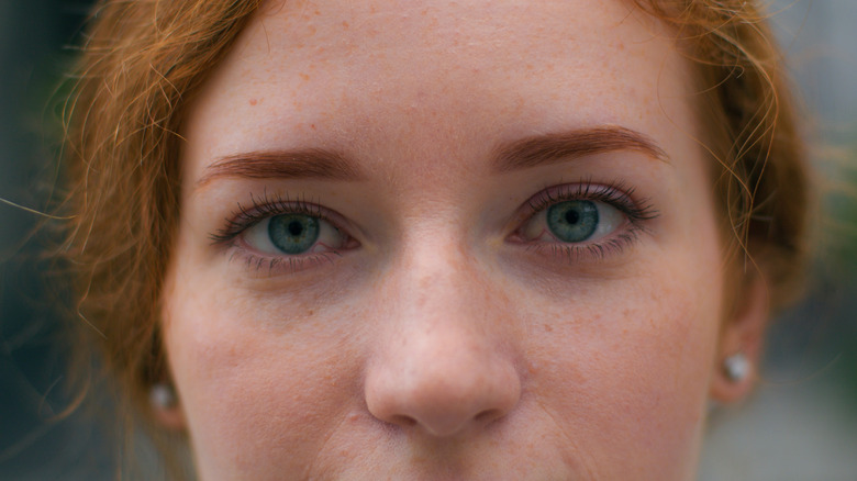 A woman with red hair and blue eyes looking into camera