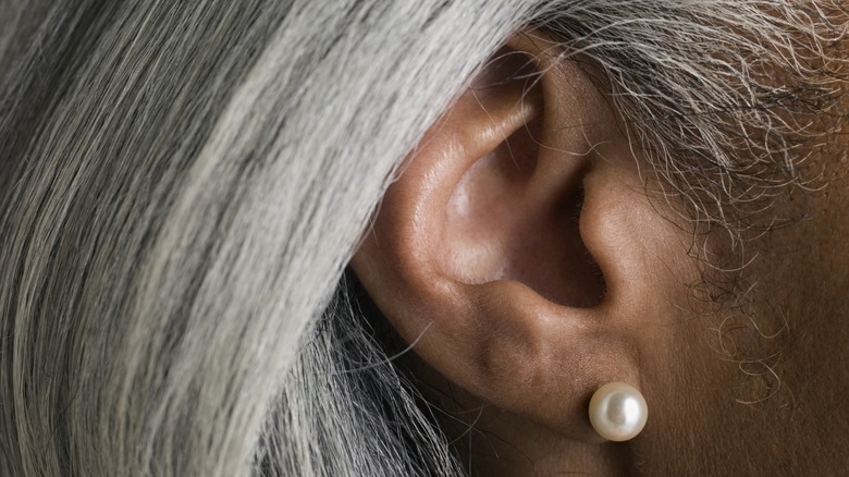 A closeup of a person's ear wearing a pear earring