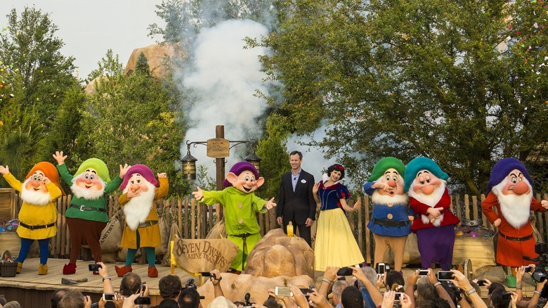Snow White and the seven dwarfs on stage with a Disney employee at Walt Disney World
