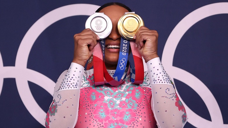 Rebecca Andrade putting her Olympic medals over her eyes in 2020