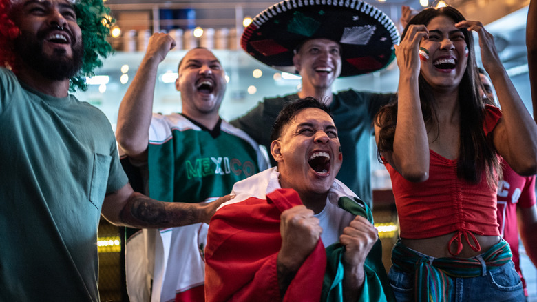A woman holding a small Mexican flag above her head