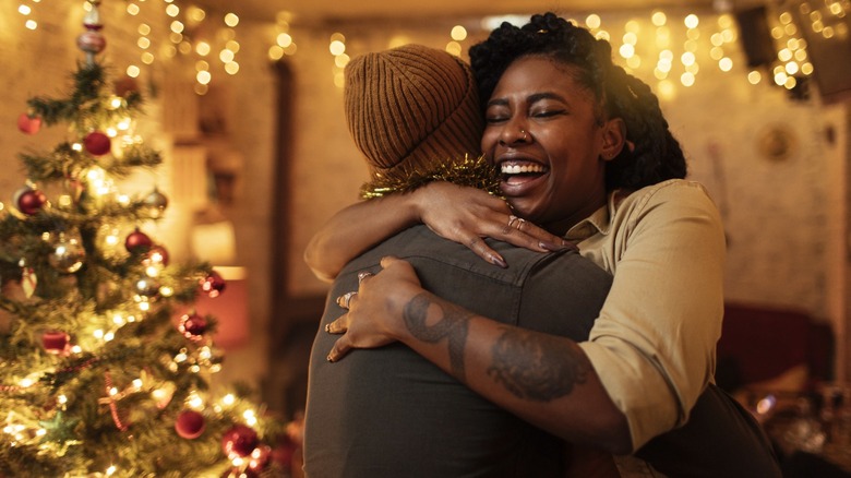 Two people hugging in front of a Christmas treee
