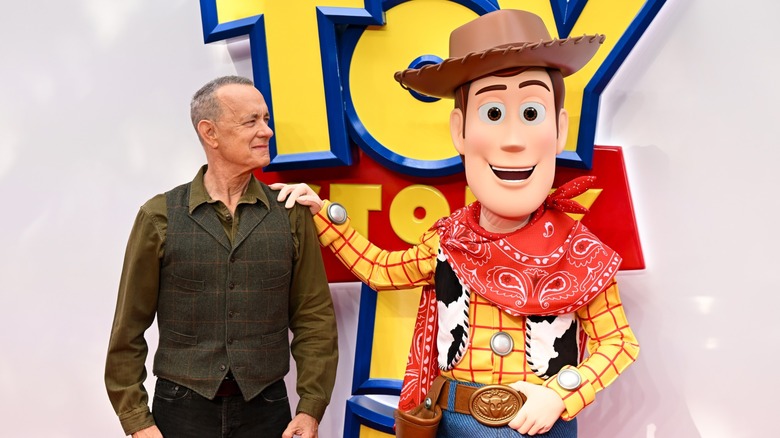 Tom Hanks posing with a person in a Woody costume at the premiere of Toy Story 5