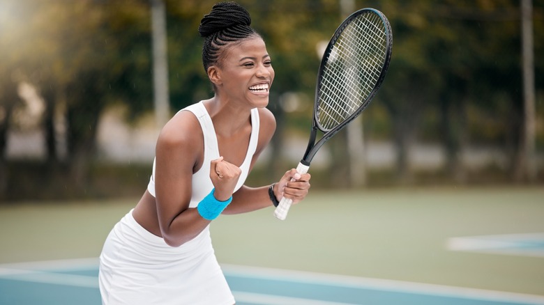 A woman smiling while playing tennis