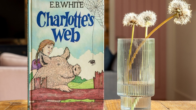 The book Charlotte's Web next to a vase with a dandelion in it