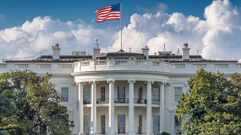 The front of the White House with a flag flying in the breeze
