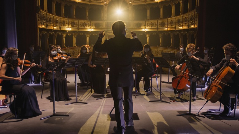 A conductor directing an orchestra on stage