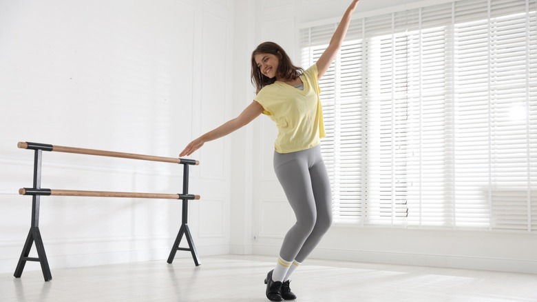 A woman tap dancing in an empty dance studio
