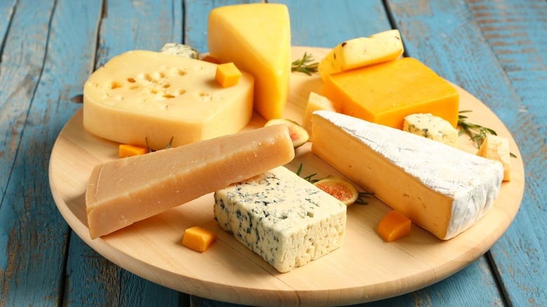 A round cheesboard with multiple different cheeses