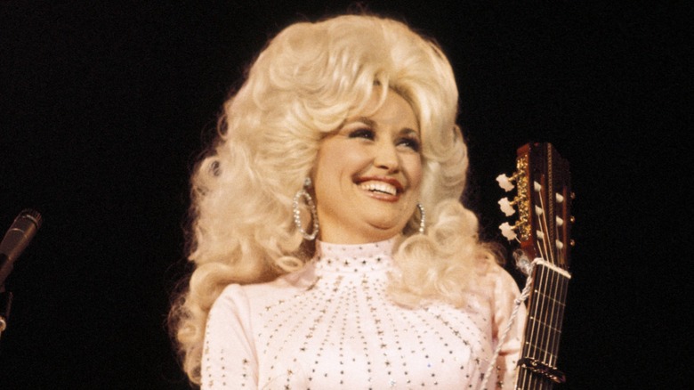 Dolly Parton onstage with teased hair and a guitar