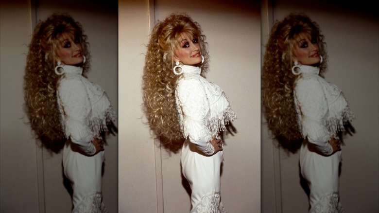 Dolly Parton posing in a white fringed dress