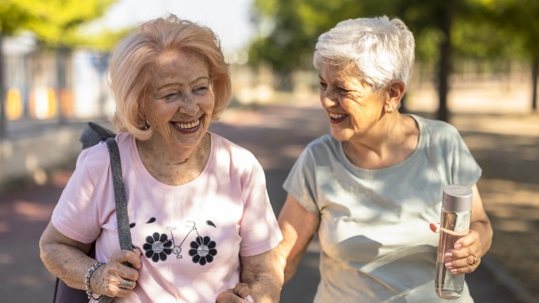 Two older women smiling at each other while on a walk