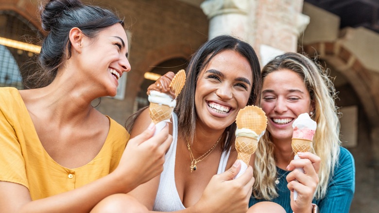 Three women smiling while eating ice creams
