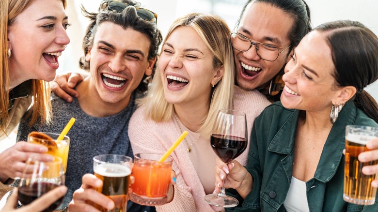A group of friends laughing together while holding drinks
