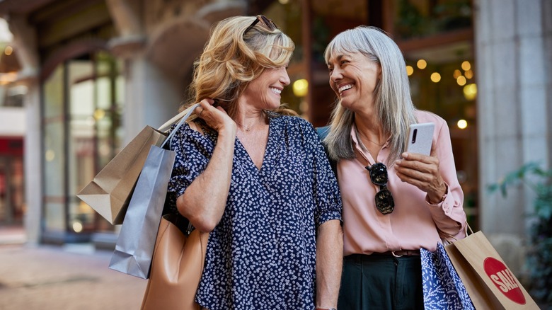 Two older women smiling at each other during a shopping trip