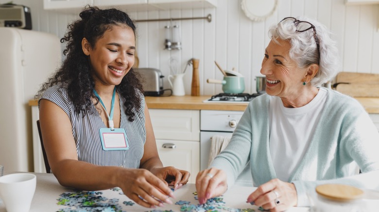 A younger woman doing a jigsaw with an older woman