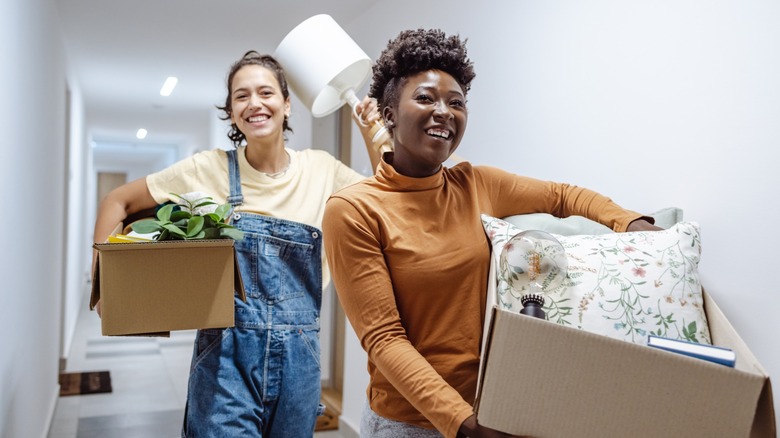 Two women smiling while moving boxes together