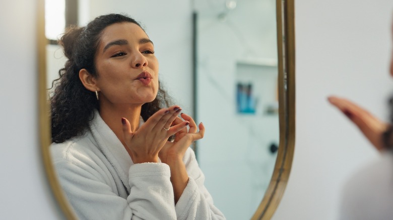 A woman blowing a kiss to herself in the mirror