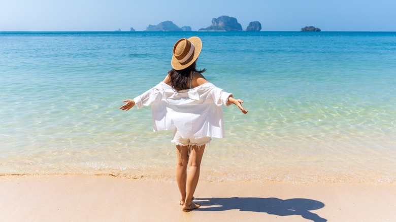 A woman standing on the beach with her arms outstretched in front of the ocean