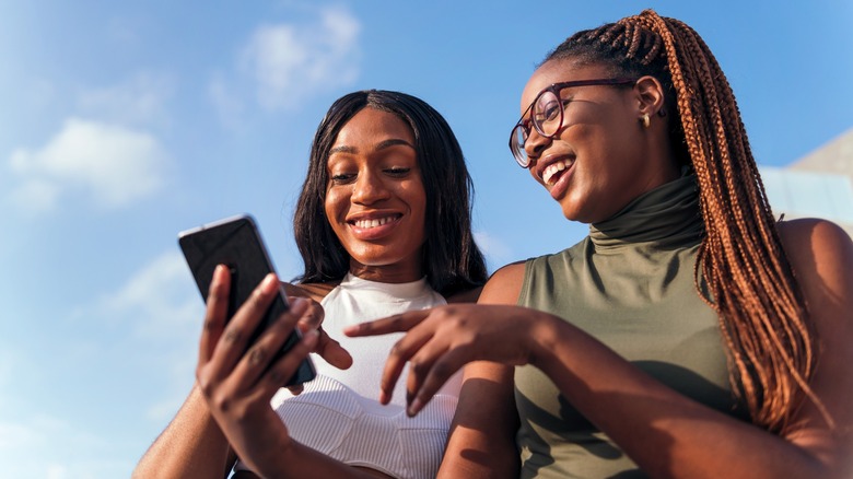 Twi friends smiling and looking at a phone