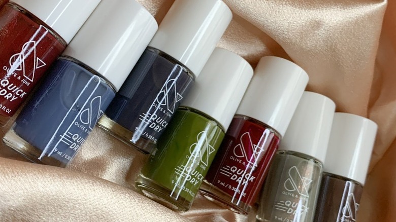 An assortment of Olive & June nail polishes arranged against a shimmery fabric