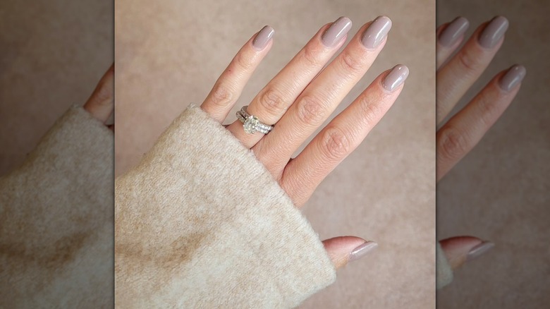An open hand wearing a sparkly ring and cream sleeve and showing the neutral shade Lowkey Perfect from Olive & June