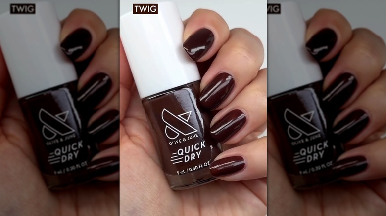 Close up of four nails against an Olive & June nail polish bottle showing off the brown shade Twig