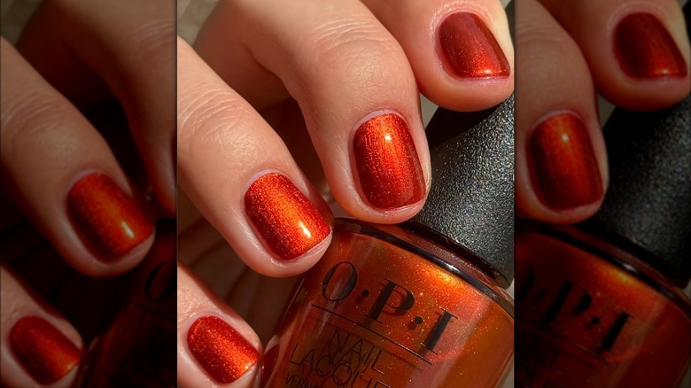 A woman wearing the orange OPI shade Liquid Fire on Instagram