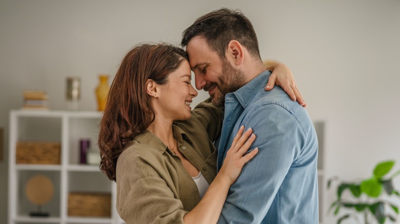A couple smiling and embracing while in their home
