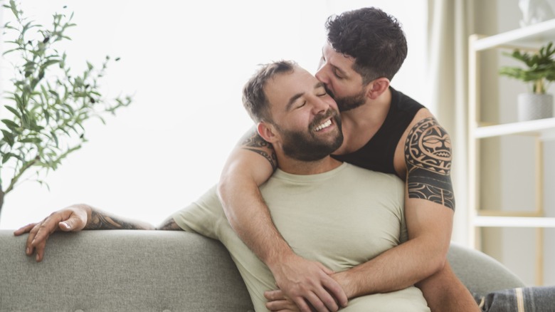 A man kissing his boyfriend on the side of his head