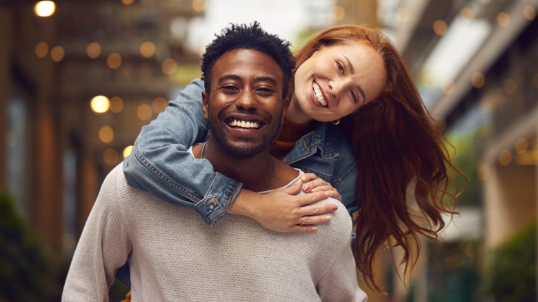 A couple smiling while the man gives the woman a piggyback