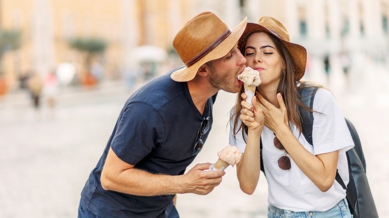 A man stealing a bite of a woman's ice cream