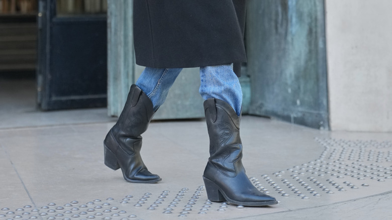 A person wearing black cowboy boots