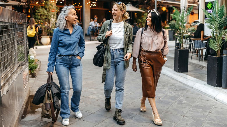 Three women walking, two wearing jeans