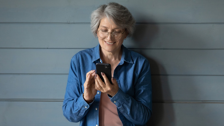A view of a woman from the back who is looking down at a dating app on a phone