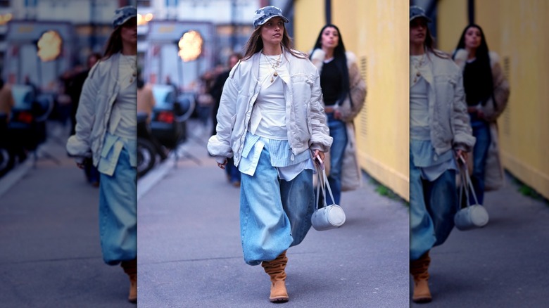 A woman in Paris wearing baggy jeans with several shirts and a ball cap