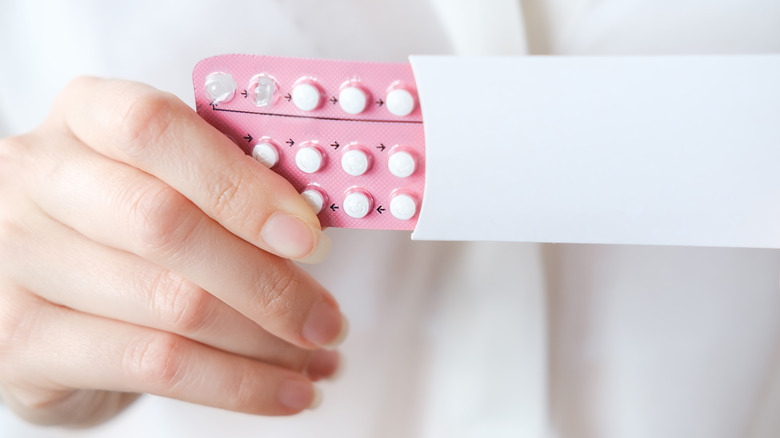 Woman holding birth control pills