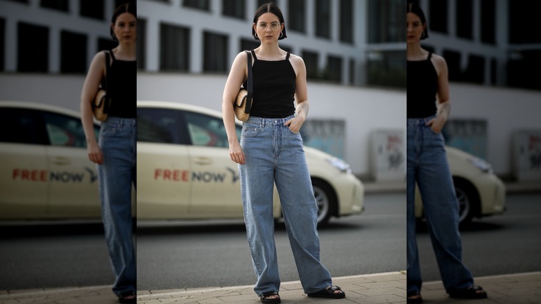 A woman wearing a black top and curved leg jeans outside