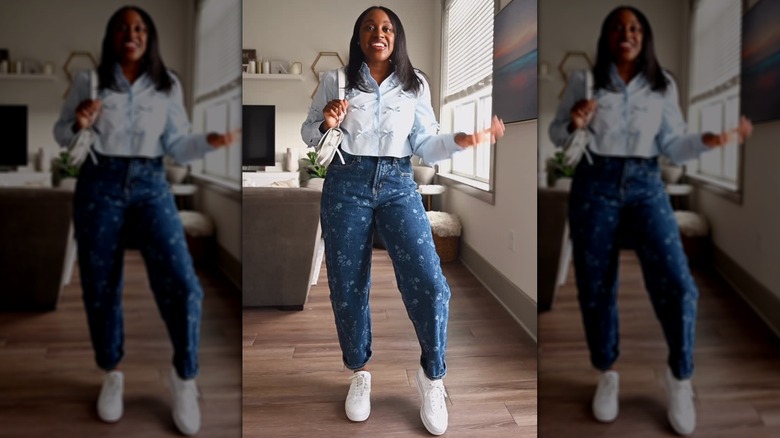 A woman in a cropped shirt and floral jeans with white sneakers