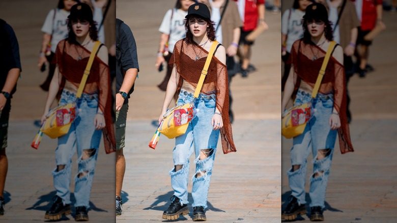 A woman wearing heavily ripped jeans with a net top and chunky boots