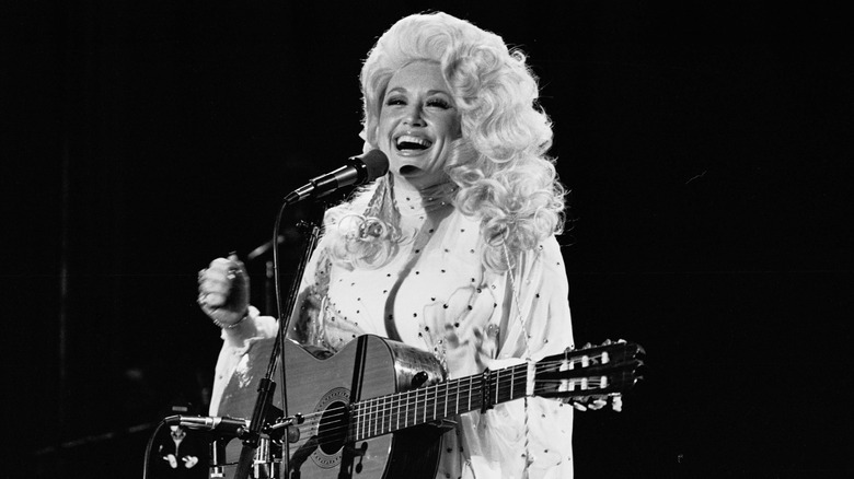 Dolly Parton on stage holding a guitar