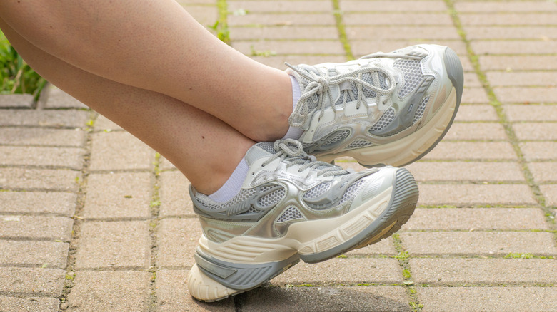 Crossed feet in white trainer sneakers with thick soles