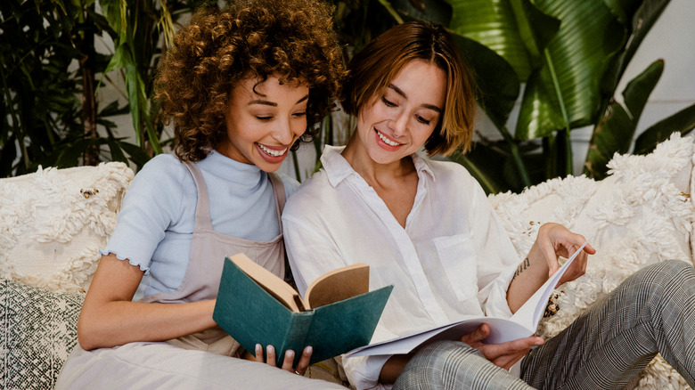 Two women reading books on sofa