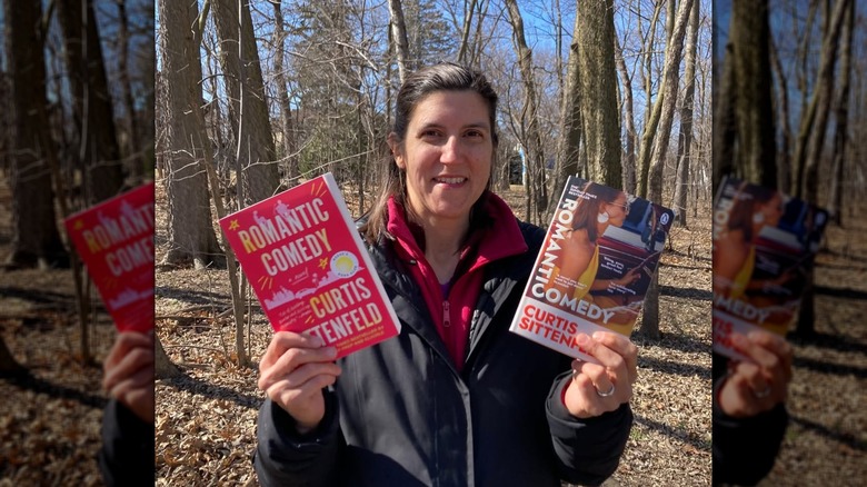 Curtis Sittenfeld holding two copies of her novel "Romantic Comedy," showing two alternate covers