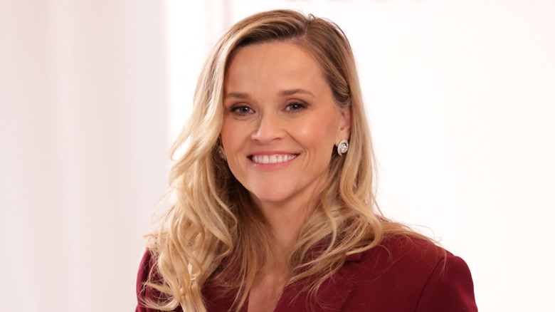 Reese Witherspoon wearing a red coat, smiling for a photo