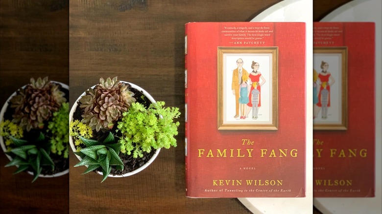 A copy of the book "The Family Fang" laying on a table next to a succulent plant